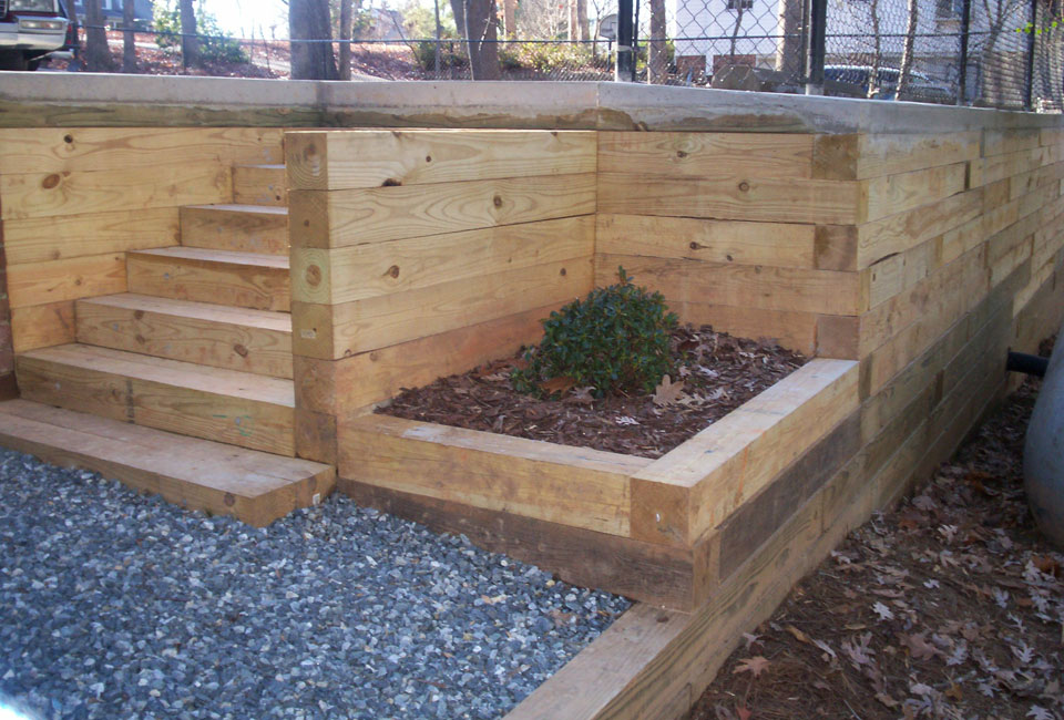 Pressure Treated Timber Retaining Walls w/ Timber Stairs, Border & Mini Planter below Poured Concrete Driveway & Black Chain Link Fence