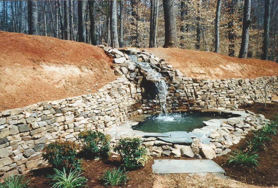 Large Scale Tennessee Fieldstone Retaining Wall w/ Steep Flowing Stream & Waterfall Into Pond w/ Recirculating Water  through BioFilter & skimmer filter inside pump house hidden by Carla Bluestone Flagstones